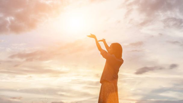 Silueta de mujer rezando sobre el hermoso fondo del cielo - Foto, imagen