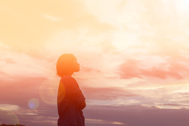 Σιλουέτα της γυναίκας προσεύχεται πάνω από το όμορφο φόντο του ουρανού - Φωτογραφία, εικόνα