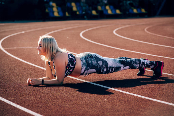 Gelukkig jonge overgewicht vrouw in activewear onder opleiding over Stadion - Foto, afbeelding