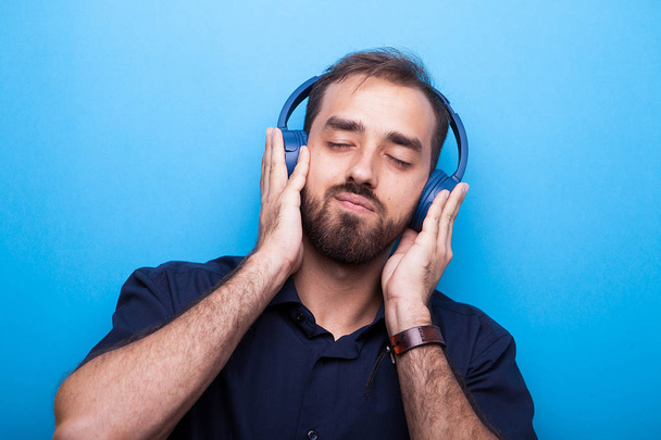 Handsome young man listening to music through headphones - Photo, Image