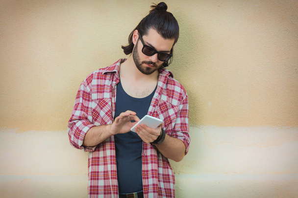 καλαίσθητο άνθρωπος χρησιμοποιώντας smartphone ενώ στέκεται σε μπεζ φόντο  - Φωτογραφία, εικόνα