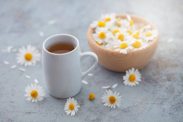 chamomile tea with fresh flowers in wooden bowl, healthy lifestyle concept  - Photo, Image