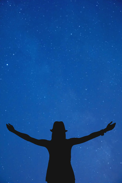 черный женский силуэт с поднятыми руками на темно-синем ночном небе
  - Фото, изображение