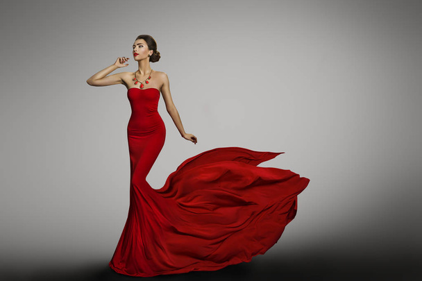 Woman Red Dress, Fashion Model in Long Silk Sexy Gown, Waving Flying Fabric Tail Train, Cloth Fluttering on Wind, Girl dancing over gray background - Fotografie, Obrázek