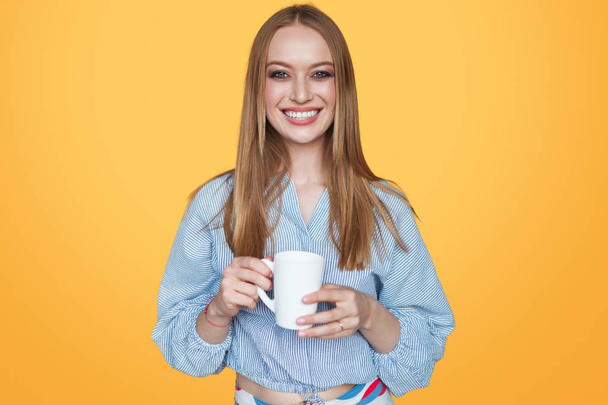 Woman smiling with cup in studio - Фото, зображення
