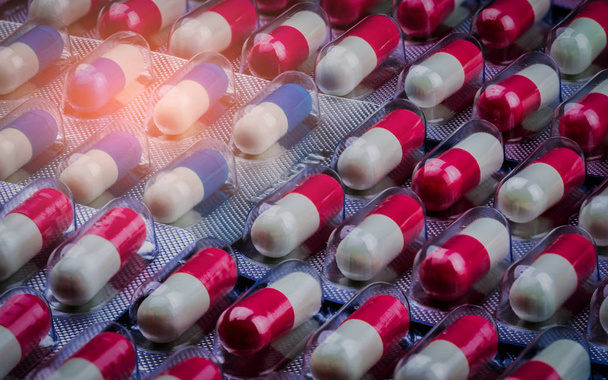 Lähikuva vaaleanpunainen-valkoinen ja sinivalkoinen antibioottien kapseli läpipainopakkauksessa. Mikrobilääkeresistenssi. Lääketeollisuus. Maailmanlaajuinen terveydenhuolto Apteekkitausta. Amoksisilliini kapseli pillereitä
.  - Valokuva, kuva