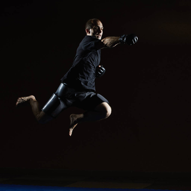 Un homme en t-shirt noir bat avec sa main dans un saut
 - Photo, image