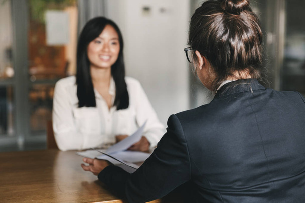 Business, career and placement concept -photo from back of businesswoman interviewing and talking with female applicant during job interview - Foto, afbeelding