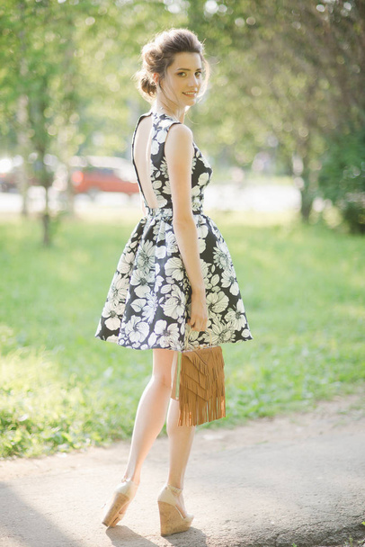 girl in summer dress looking back with handbag in hands on heels - Foto, afbeelding
