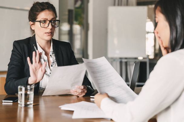 Image of nervous unsure asian woman talking and negotiating with businesswoman while sitting at table in office during job interview - business, career and recruitment concept - Foto, Bild
