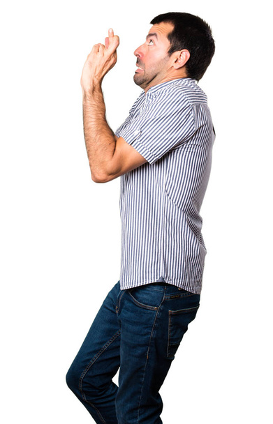 Handsome man with his fingers crossing on isolated white background - Φωτογραφία, εικόνα