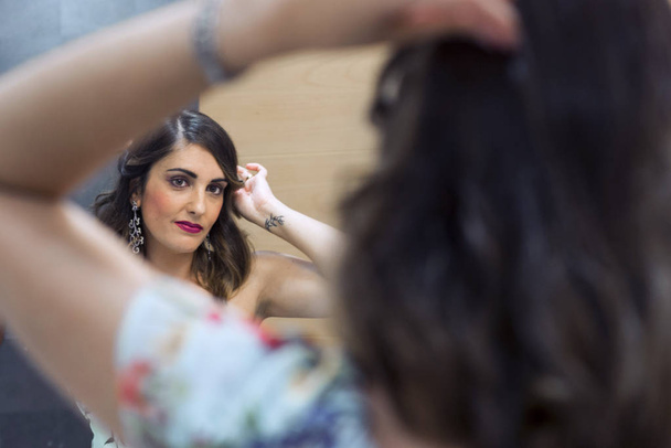 Piękna kobieta czesanie jej włosy i Makijaż przed lustrem. - Zdjęcie, obraz
