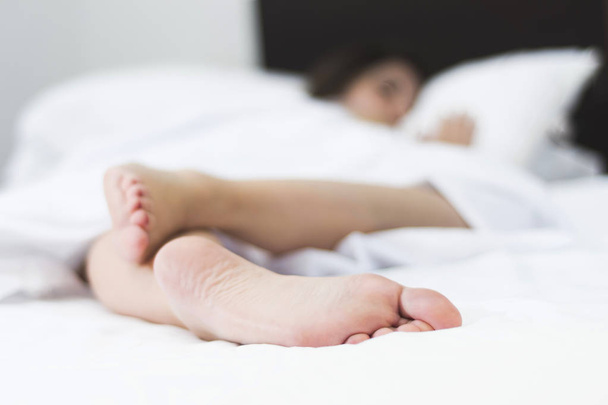 pieds de femme endormie à l'envers sur un lit blanc avec une faible profondeur de champ
 - Photo, image