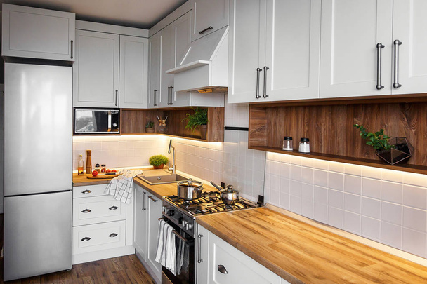 Stijlvolle lichte grijze keuken interieur met moderne kasten en roestvrijstalen apparaten in de nieuwe woning. het ontwerp van de keuken in Scandinavische stijl. groene planten decor, houten aanrecht, gootsteen - Foto, afbeelding