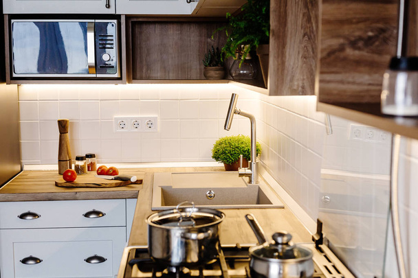 Moderní design kuchyně ve skandinávském stylu. světle šedé kuchyni stylový interiér s moderním nábytkem a nerezové spotřebiče. Dřevěná deska, ocelová kamna, Rada, nůž a koření - Fotografie, Obrázek
