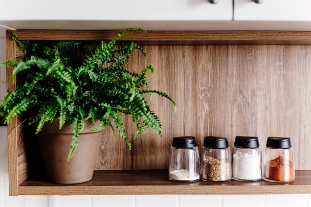 prateleira de madeira com moinho de pimenta e especiarias e plantas verdes na cozinha moderna. cozinhar comida. Elegante cozinha design de interiores em estilo escandinavo
 - Foto, Imagem