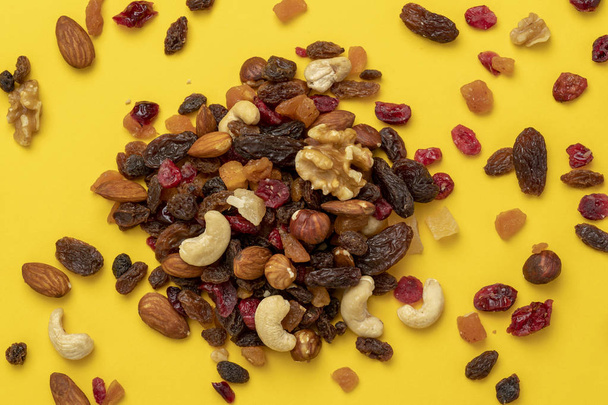 Close up of mix of dried fruits and nuts on a yellow background - Photo, Image
