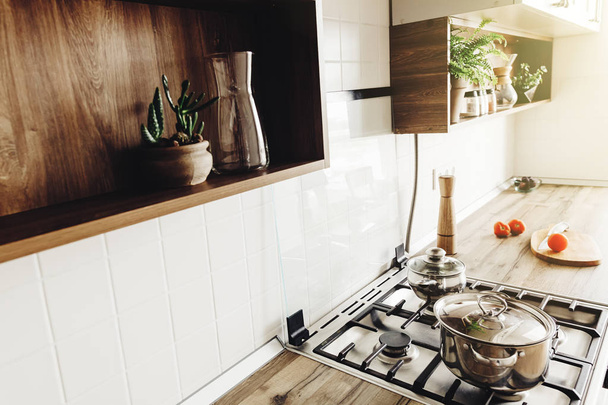 北欧風のモダンなキッチンで調理。スタイリッシュなグレー キッチン インテリア デザイン モダンな家具、ステンレス器具。木製カウンター、スチール ストーブ、ボード、ナイフ、スパイス - 写真・画像