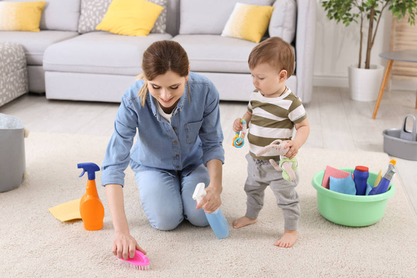 Housewife with little son cleaning carpet in room - Foto, Imagen