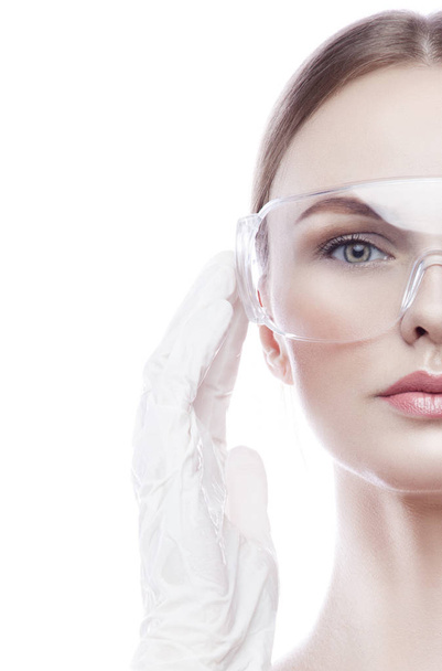 Half of young woman portrait with natural makeup in eye-shield and surgical gloves - Photo, Image