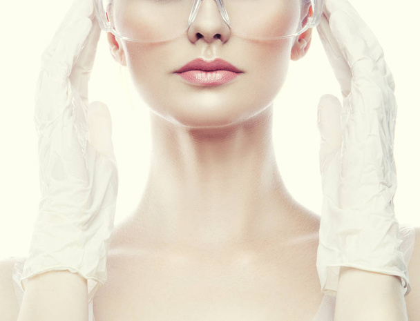 Обрезанный портрет молодой женщины с натуральным макияжем в глазном щите и хирургических перчатках
 - Фото, изображение