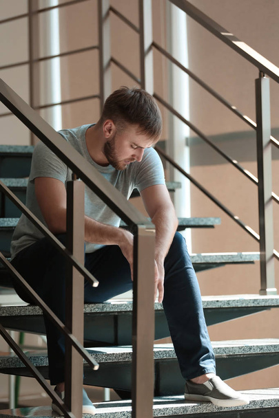 Depressed young man sitting on stairs - Fotografie, Obrázek