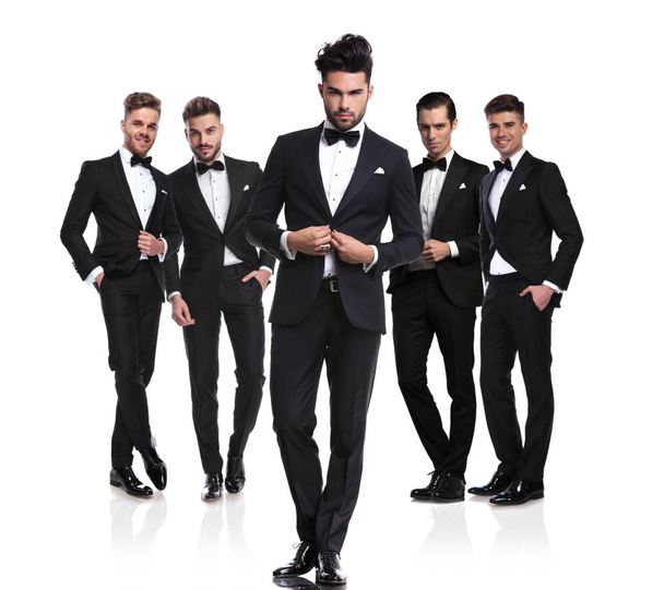 five handsome grooms with leader buttoning suit in front of them, standing on white background, full length picture - Photo, Image