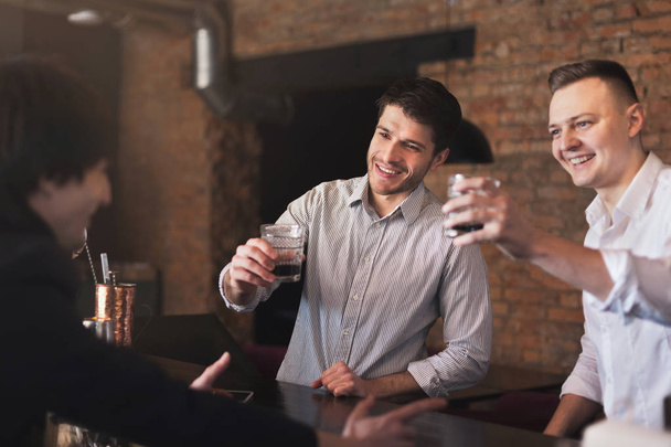Amigos alegres en el bar comunicándose con el camarero
 - Foto, imagen