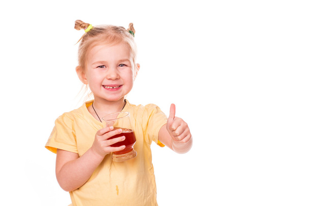 Linda niña sosteniendo el vaso con jugo sonriendo con el pulgar hacia arriba
 - Foto, imagen