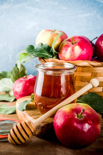Juutalainen loma Rosh Hashanah tai omena juhlapäivä konsepti, jossa punaiset omenat, omenanlehdet ja hunaja purkissa, vaaleansininen ja puinen tausta kopioi tilaa
 - Valokuva, kuva