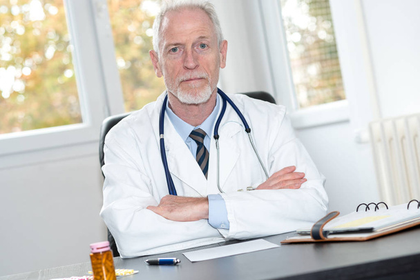 Portrait of senior doctor sitting in office - Photo, Image