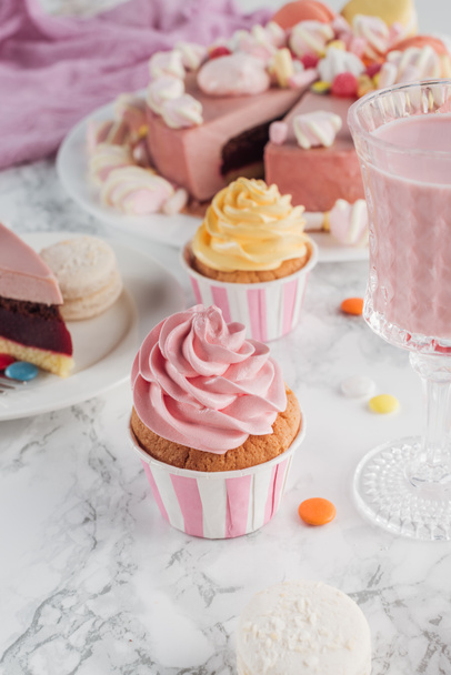 close up of birthday cupcakes, pink cake and milkshake in glass on marble table  - Photo, image