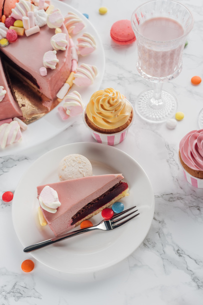 high angle view of birthday cake and cupcakes and milkshake in glass on table  - Valokuva, kuva