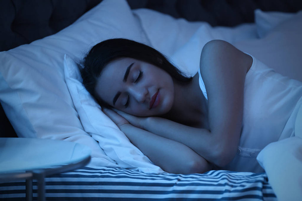 Молода жінка спить у ліжку вночі. Час сну
 - Фото, зображення