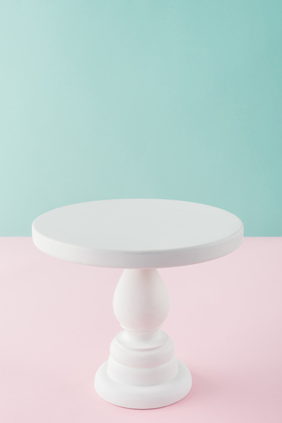 soporte de pastel blanco vacío sobre fondo rosa y turquesa con espacio para copiar
 - Foto, imagen