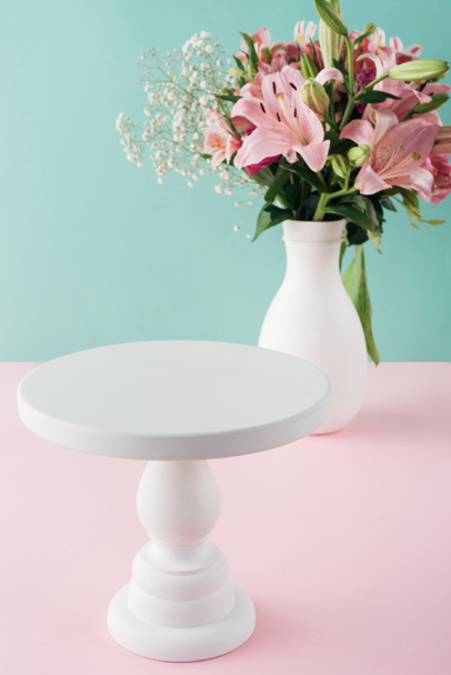 leerer weißer Kuchenständer und Blumenstrauß in der Vase  - Foto, Bild