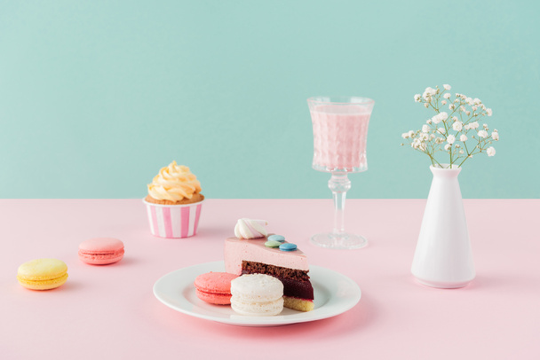 macarons, cupcake, piece of cake and milkshake on pastel background - Photo, Image