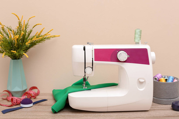 Modern sewing machine on table against light background - Foto, Imagen