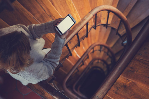 Fille utilisant un téléphone portable dans les escaliers dans le bâtiment
. - Photo, image