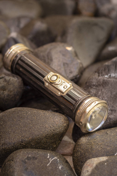 Close up shot of a antique 1920`s flashlight in pebbles background, vintage retro style concept - Fotó, kép