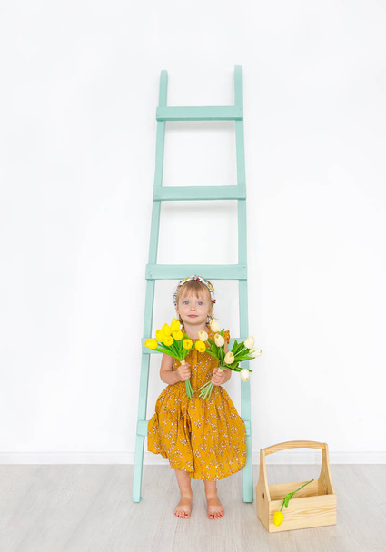 Carina bambina con i tulipani è in uno studio leggero primavera con scala. Piccola bellissima principessa. Concetto dell'infanzia felice
. - Foto, immagini