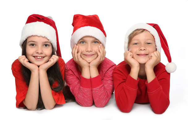 Cute little children in Santa hats on white background. Christmas celebration - Foto, Bild