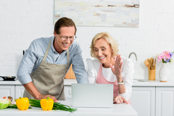 senior couple having video call and using laptop at kitchen - 写真・画像