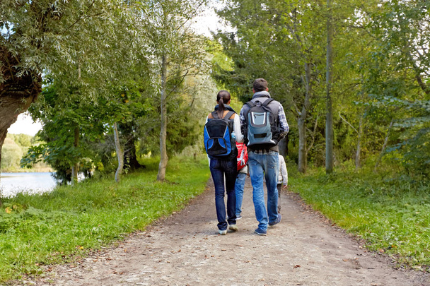 family with backpacks hiking or walking in woods - Fotoğraf, Görsel