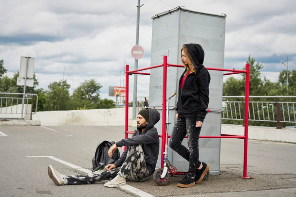 Young stylish couple with kick scooters on urban background  - Zdjęcie, obraz