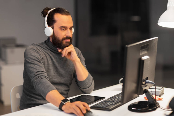 creative man in headphones working at night office - Fotoğraf, Görsel