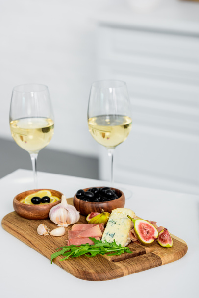 close-up view of glasses of wine and delicious snacks on wooden board on table     - Fotoğraf, Görsel