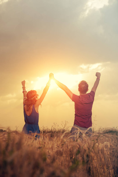 homme heureux avec femme tenant les mains levées sur la prairie au coucher du soleil
  - Photo, image