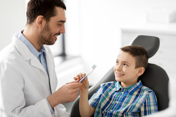 dentist giving toothbrush to kid patient at clinic - Foto, imagen
