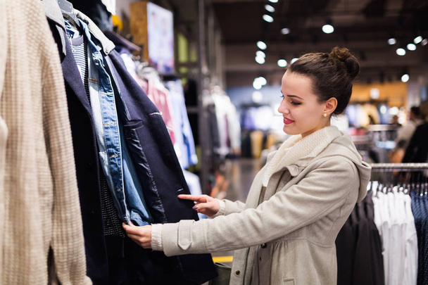 Young attractive woman buying clothes in shopping mall - Foto, Imagen